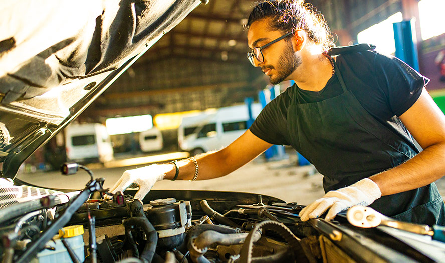 Mechanic wearing white gloves working on car engine 