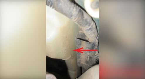 Locate the coolant reservoir, which is a fairly large plastic tank near the radiator.